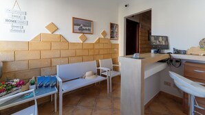 A kitchen with a counter, chairs, a sink, and a wall with a picture and a sign. - L'Oasi di Favignana Room and Charme (Favignana)
