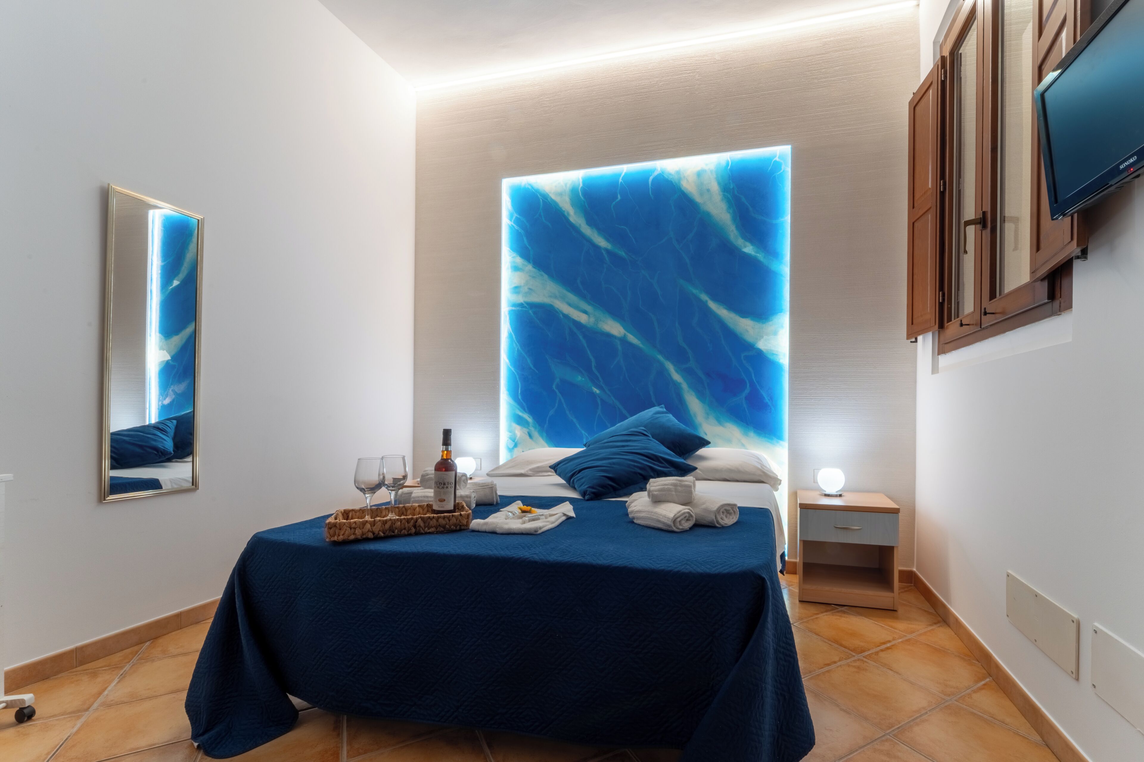 Une chambre d’hôtel comprenant un lit, une table de chevet, une commode, un miroir et un téléviseur.