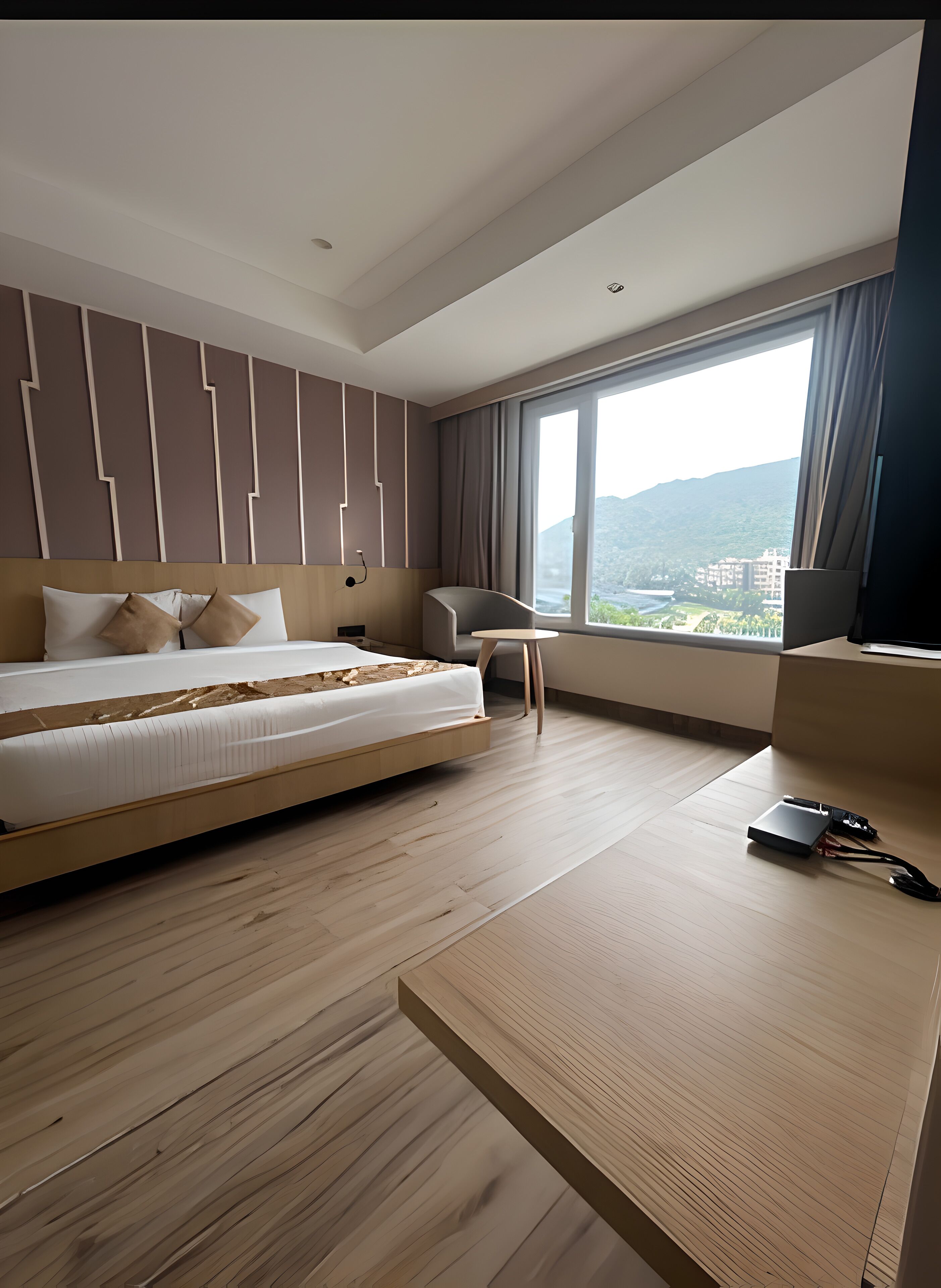 A modern hotel room with a large bed, a desk, and a view of a mountainous landscape.