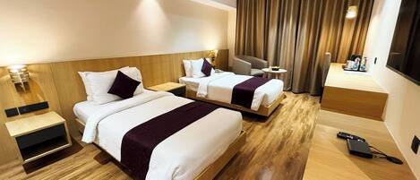Ein Hotelzimmer mit zwei Betten, einem Schreibtisch, einem Sessel und einem Fernseher.