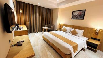 A hotel room with a bed, bedside tables, a desk, a chair, a TV, and a curtain.