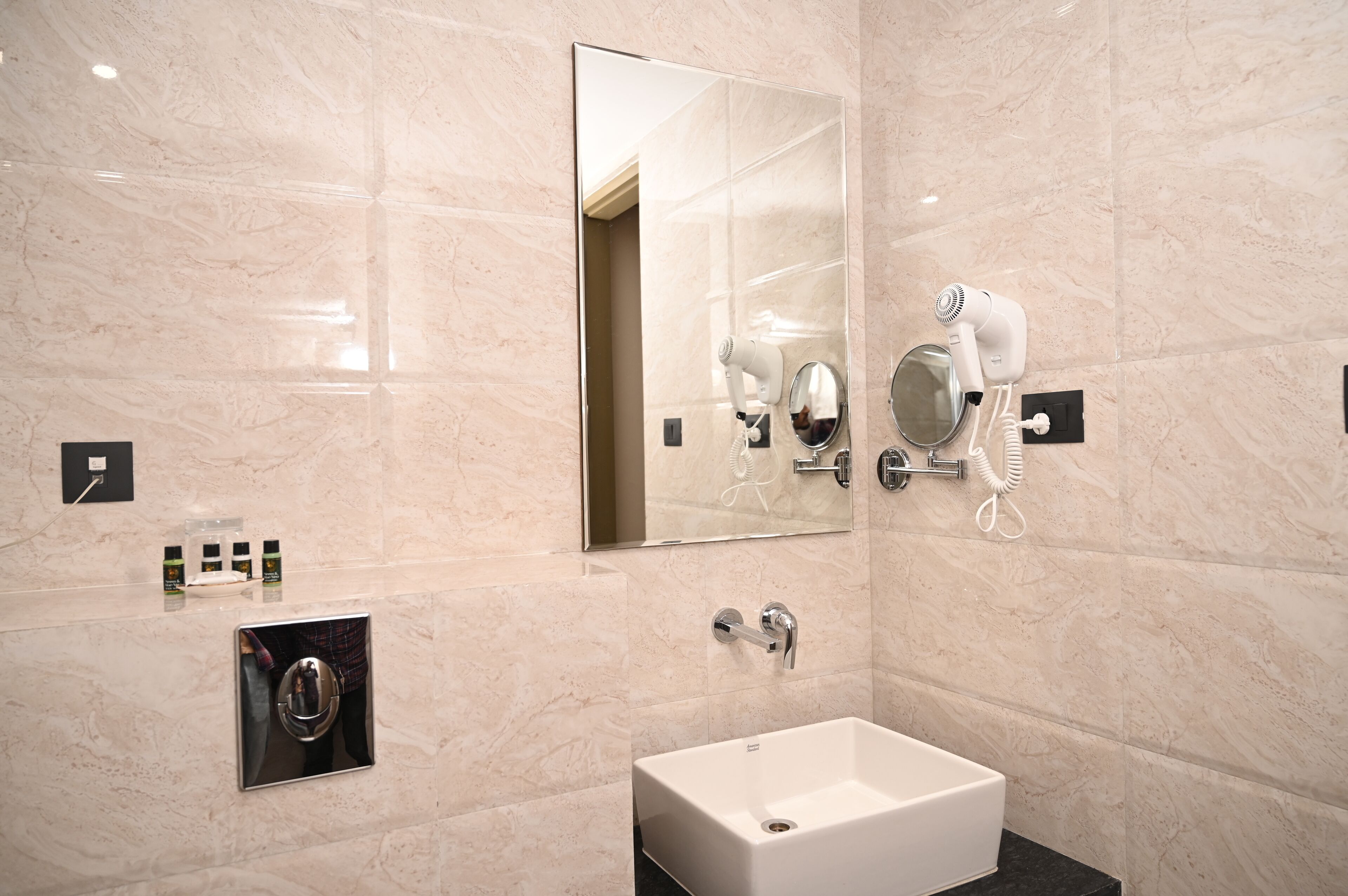 Een moderne badkamer met een grote spiegel, een haardroger, een wastafel en een handdoekrek.