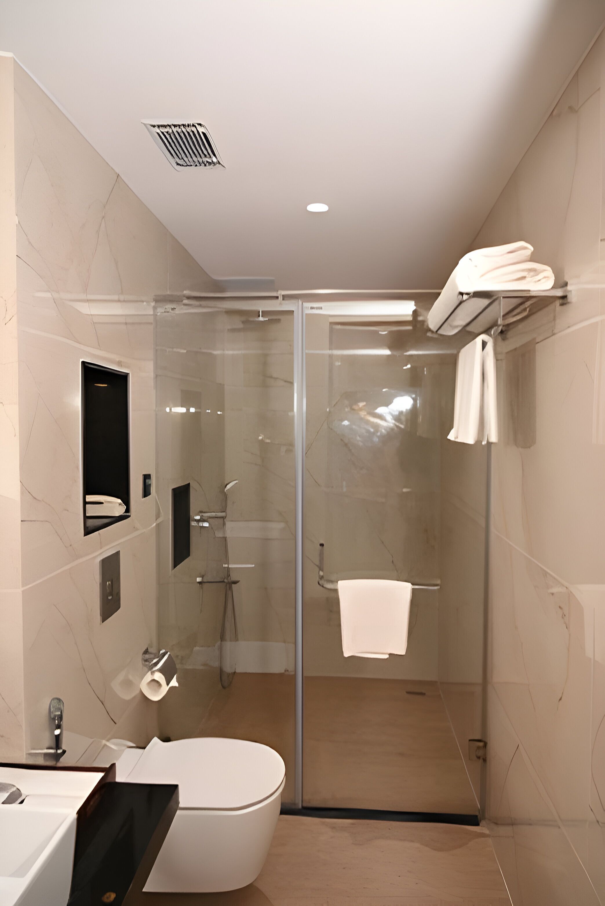 A modern bathroom with a glass-enclosed shower, a toilet, and a sink.