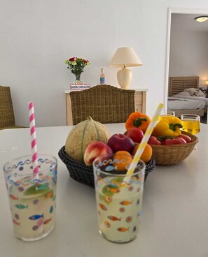 A dining table with a fruit bowl, a basket of fruits, and two glasses of a beverage with straws. - Lagrange Vacances Villa D'Este (Arcachon)
