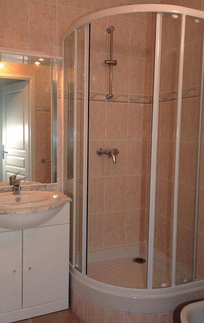 A bathroom with a glass-enclosed shower, a sink with a mirror, and a toilet.