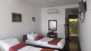Een hotelkamer met twee bedden, een bureau, een spiegel en een aan de muur bevestigde televisie.