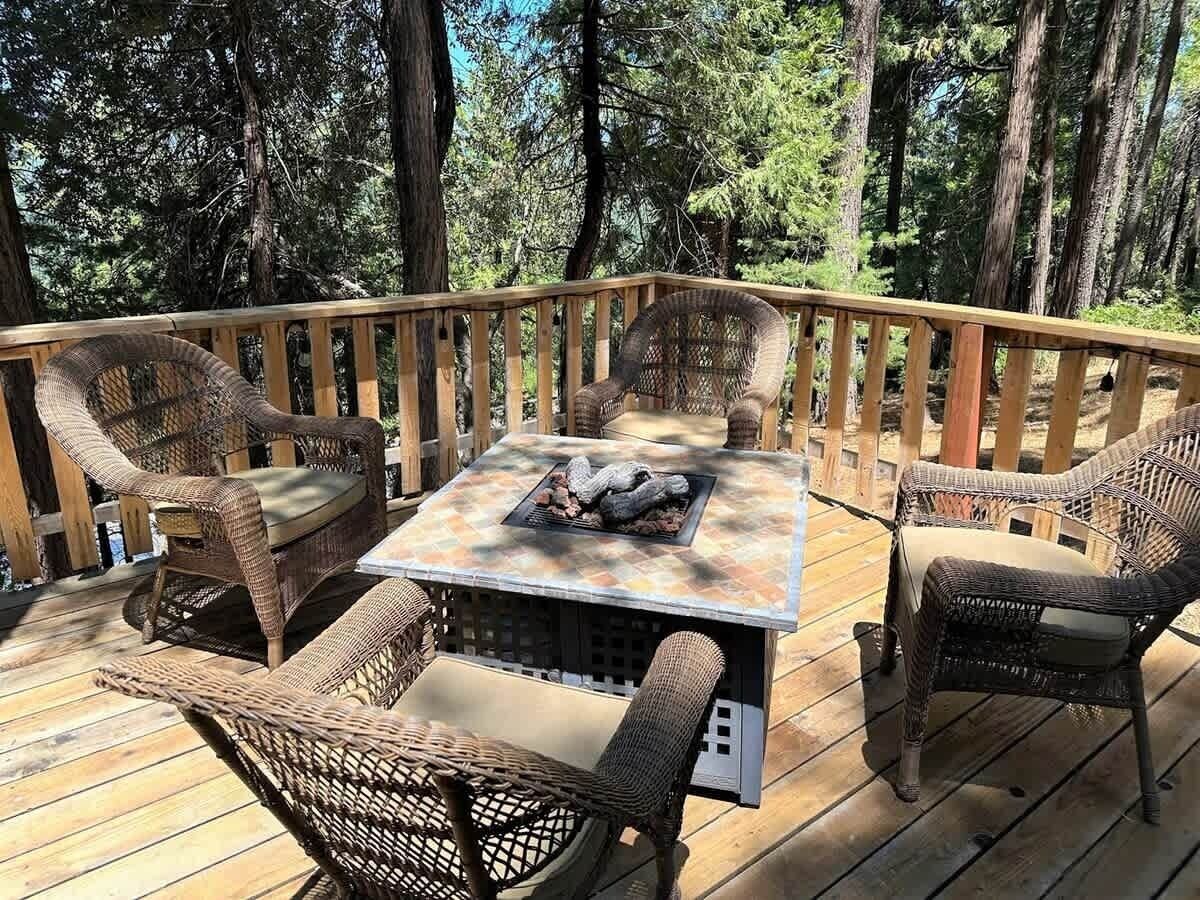 An outdoor deck with wicker furniture and a square table with a fire feature.