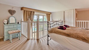 Ein Schlafzimmer mit Bett, Schminktisch, Spiegel und Balkon mit Blick.
