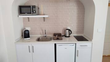 Een kleine keuken met een magnetron, waterkoker, koffiezetapparaat en vaatwasser.