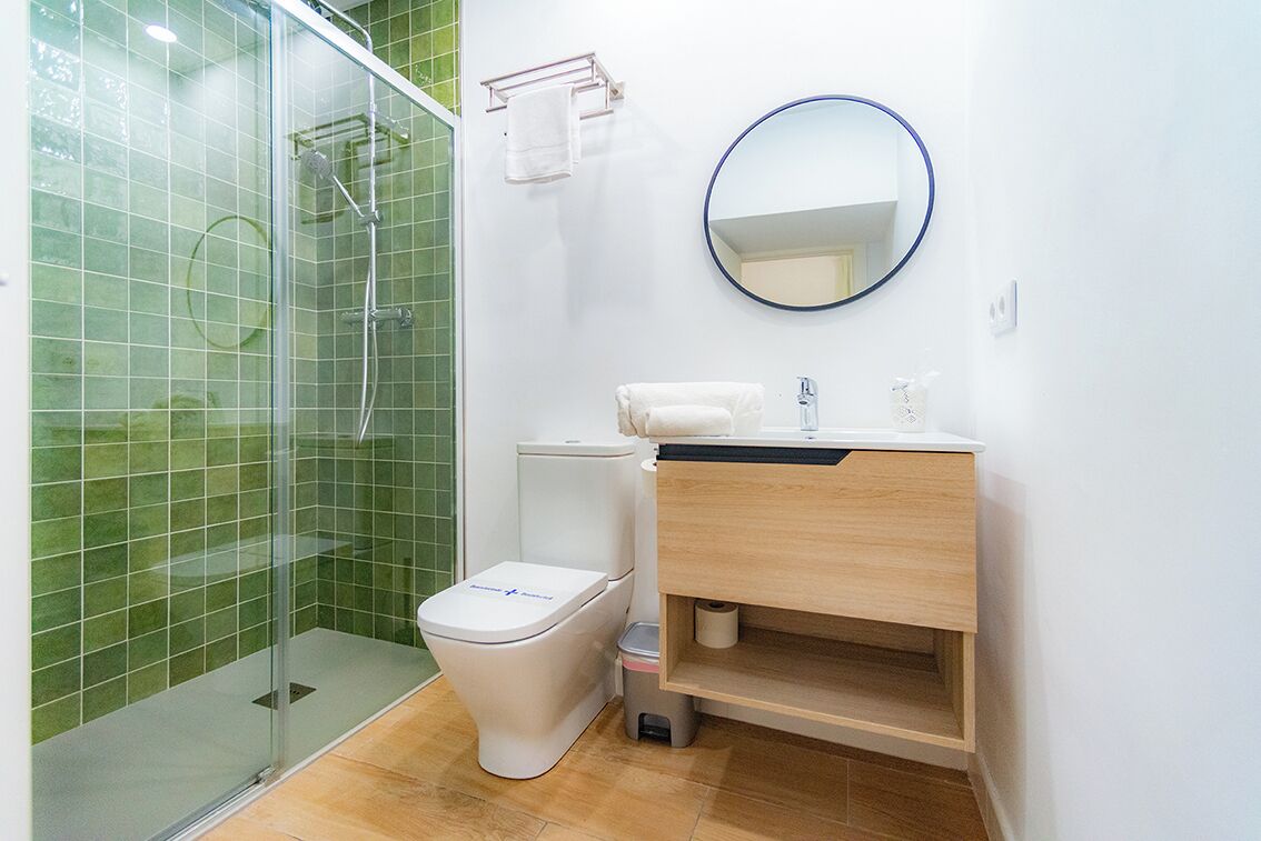 Une salle de bain avec une douche à parois de verre, des toilettes, un lavabo avec un miroir et un porte-serviettes.