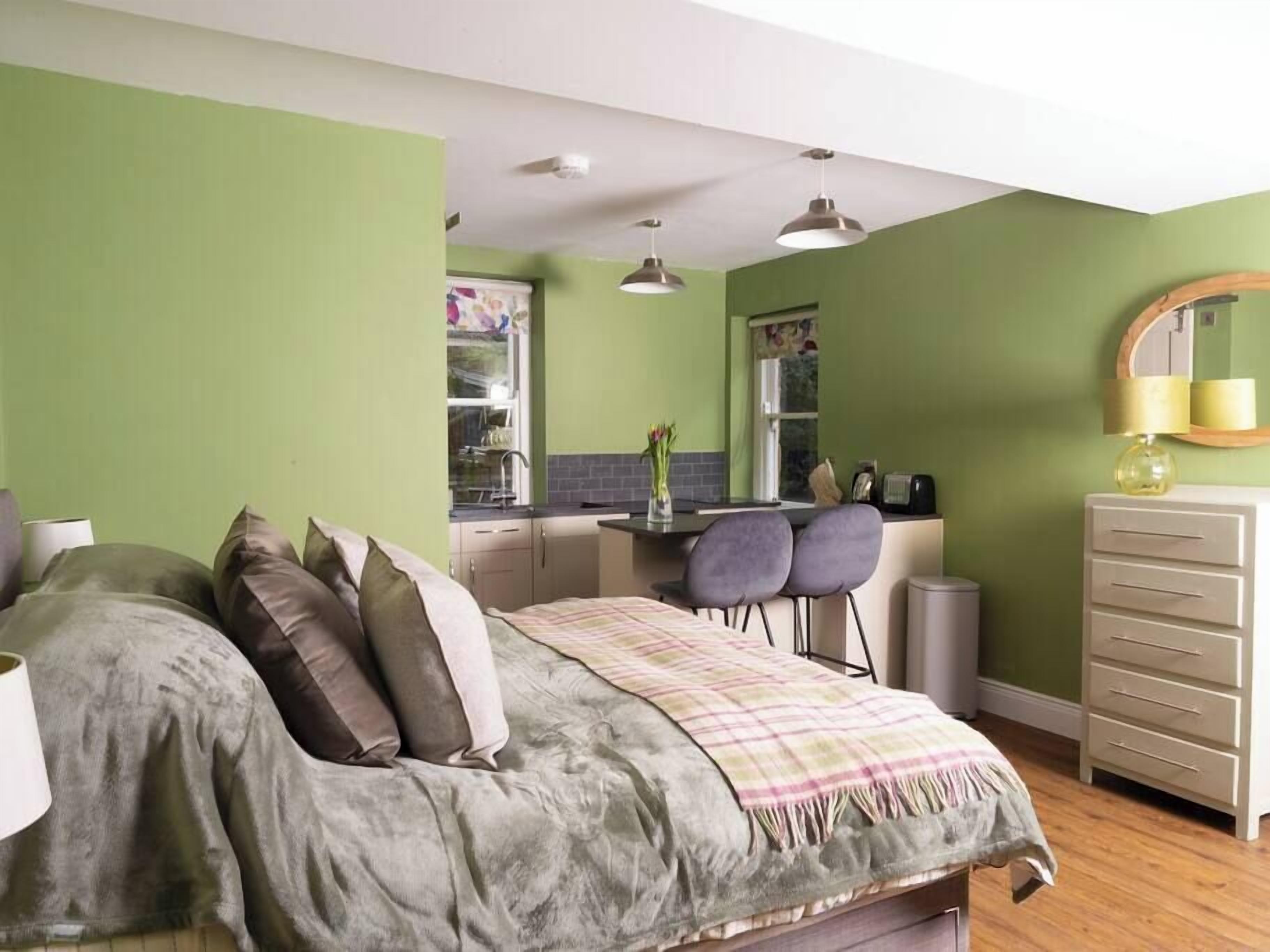 Une chambre compacte comprenant un lit, une table de chevet et un petit coin cuisine.