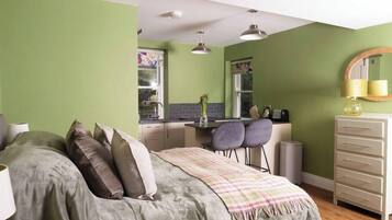 Une chambre compacte comprenant un lit, une table de chevet et un petit coin cuisine.
