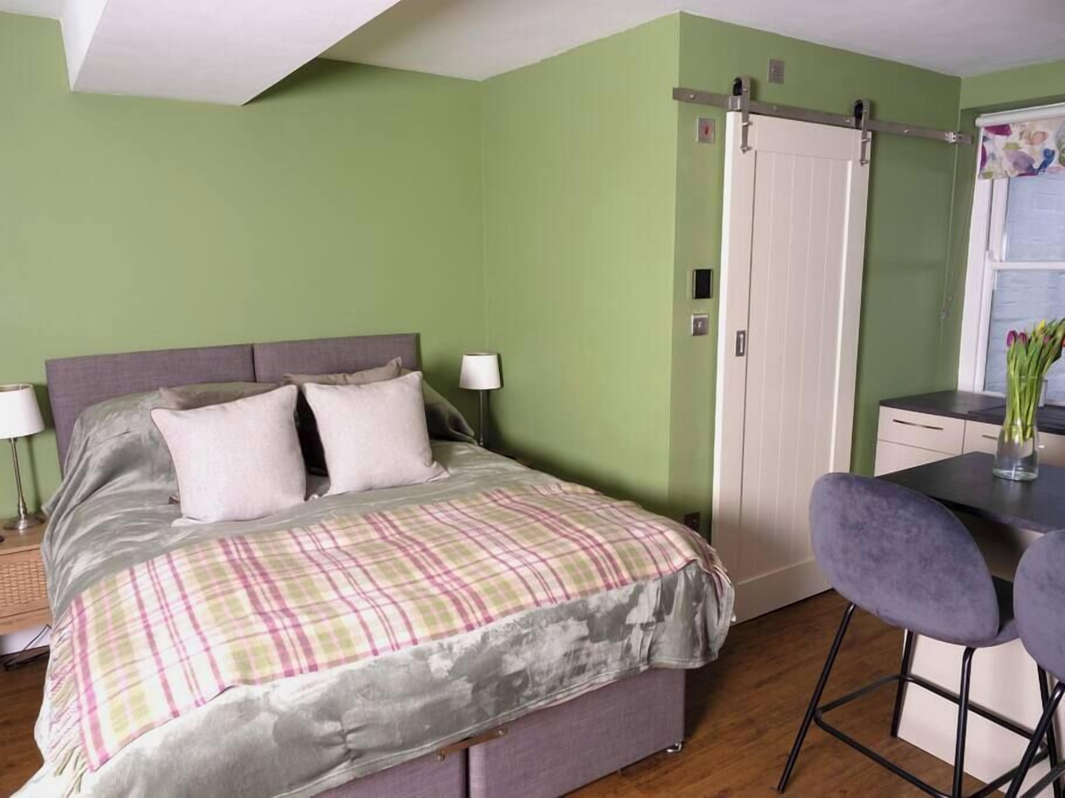 A bedroom with a bed, bedside lamps, a desk, and a chair.