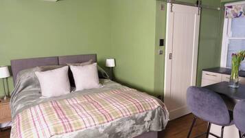 A bedroom with a bed, bedside lamps, a desk, and a chair.