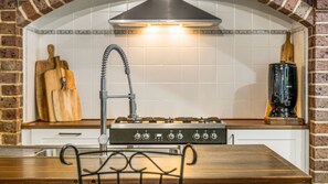 A kitchen with a gas stove, a sink with a flexible hose faucet, and a wooden table with metal chairs.