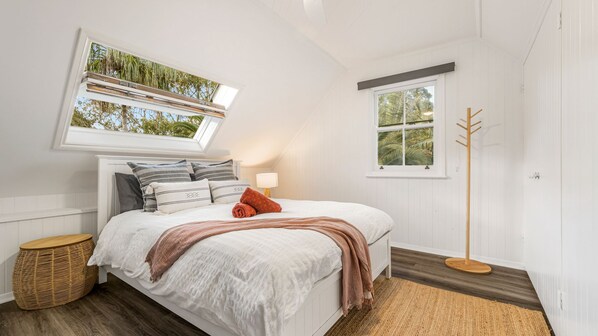 Quarto com cama, janela com vista, mesa de cabeceira e abajur.