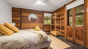 Una camera da letto con un letto, un armadio in legno, uno specchio e una finestra.