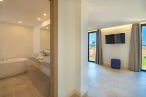 Un baño moderno con una bañera independiente, un tocador con espejo y un amplio ventanal con vistas al exterior.