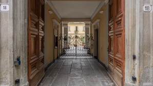 A corridor with a wrought iron gate, numbered doors, and stone flooring. - Carlo Alberto House by Wonderful Italy (Torino)