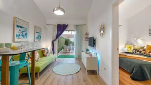 Ein modernes Wohnzimmer mit Sofa, Esstisch mit Stühlen, Fernseher und Bett.