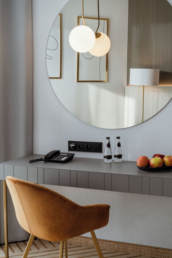 Une cuisine moderne avec un miroir rond, un luminaire suspendu et un panier de fruits posé sur le plan de travail.