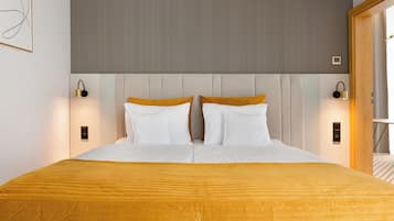 A neatly made bed with a yellow bedspread, two white pillows, and a headboard with a light gray panel.
