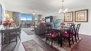 A dining area with a table, chairs, and a view through a glass door.