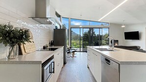 Una cocina moderna con una isla central, horno empotrado y un amplio ventanal con vistas al exterior.