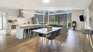 Una cocina moderna con una isla central, taburetes de bar y una mesa de comedor con sillas.