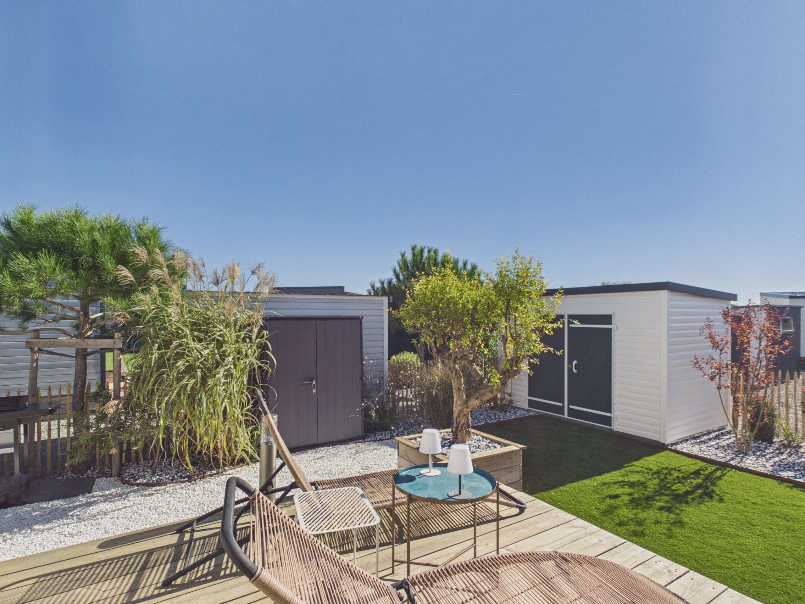 A backyard with a wooden deck, a small table with two chairs, a shed, and a well-maintained lawn.