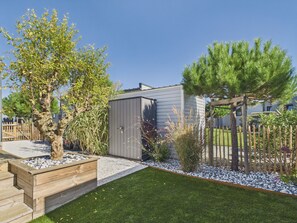A residential backyard with a wooden deck, a shed, and a well-maintained lawn.