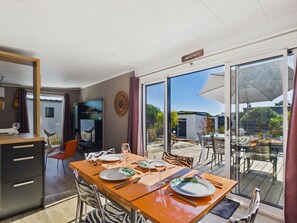 A dining area with a table set for four, a television, and a view of the outdoors.