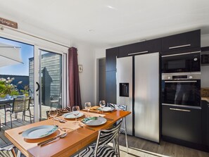 A modern kitchen with a dining area, featuring stainless steel appliances and a zebra-patterned chair.