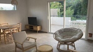 Una sala de estar moderna con comedor, televisión y balcón con mobiliario exterior.