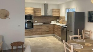Una cocina moderna con armarios de madera, electrodomésticos de acero inoxidable y un comedor con mesa y sillas.