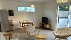 Una sala de estar moderna con comedor, televisor y un gran ventanal.