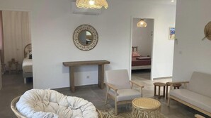 Una sala de estar moderna con un espejo redondo grande, un banco de madera, una butaca acolchada y un sofá.