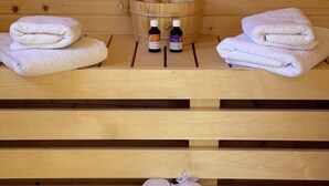 Een houten sauna bank met handdoeken en flesjes olie.