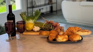 Een eettafel met eten en drinken, een televisie op de achtergrond, en een woonkamer met een bank.
