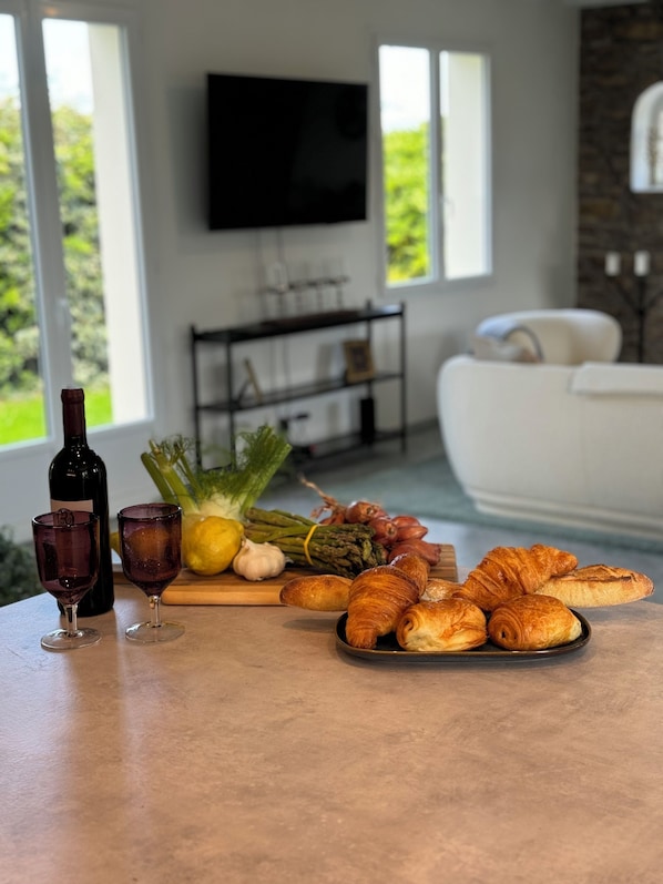 A dining table with food and drinks, a television in the background, and a living room with a couch.