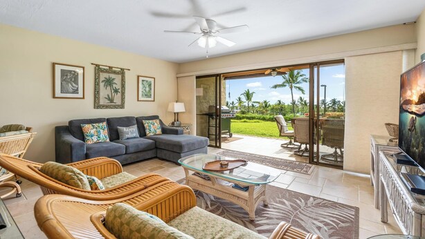 A spacious living room with a sofa, wicker chairs, a glass coffee table, and a television. - Keauhou Punahele A103 | Ground Floor Condo with Split AC and Oceanviews (Kailua-Kona)