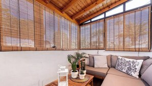 A cozy room with a wooden ceiling, a sofa with cushions, a small table with decorative items, and a potted plant.