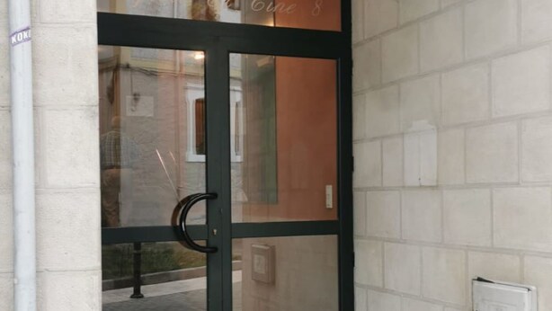 A building entrance with a glass door, a small set of steps, and a visible electrical box on the wall. - Apartamento Cinema (Cangas de Onís)