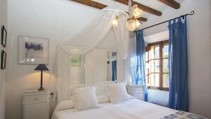 A bedroom with a bed, bedside table, lamp, and a window with curtains.