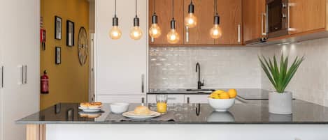 A modern kitchen with wooden cabinets, a black countertop, and a central island with stools.