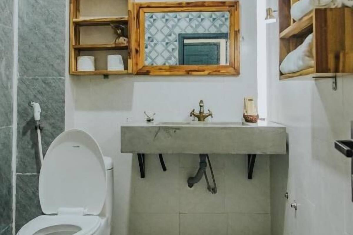A bathroom with a toilet, a sink with a mirror, and a tiled floor.