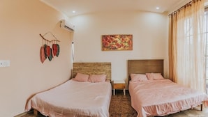 Un dormitorio con dos camas, cabecera de madera, aire acondicionado de pared y un cuadro con motivos florales.