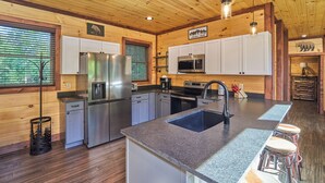 A modern kitchen with granite countertops, stainless steel appliances, and a central island with bar stools.