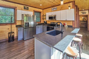 A modern kitchen with granite countertops, stainless steel appliances, and a central island with bar stools.
