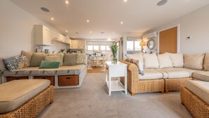 Un amplio espacio de sala con un conjunto de sofás, una mesa de comedor y una cocina al fondo.